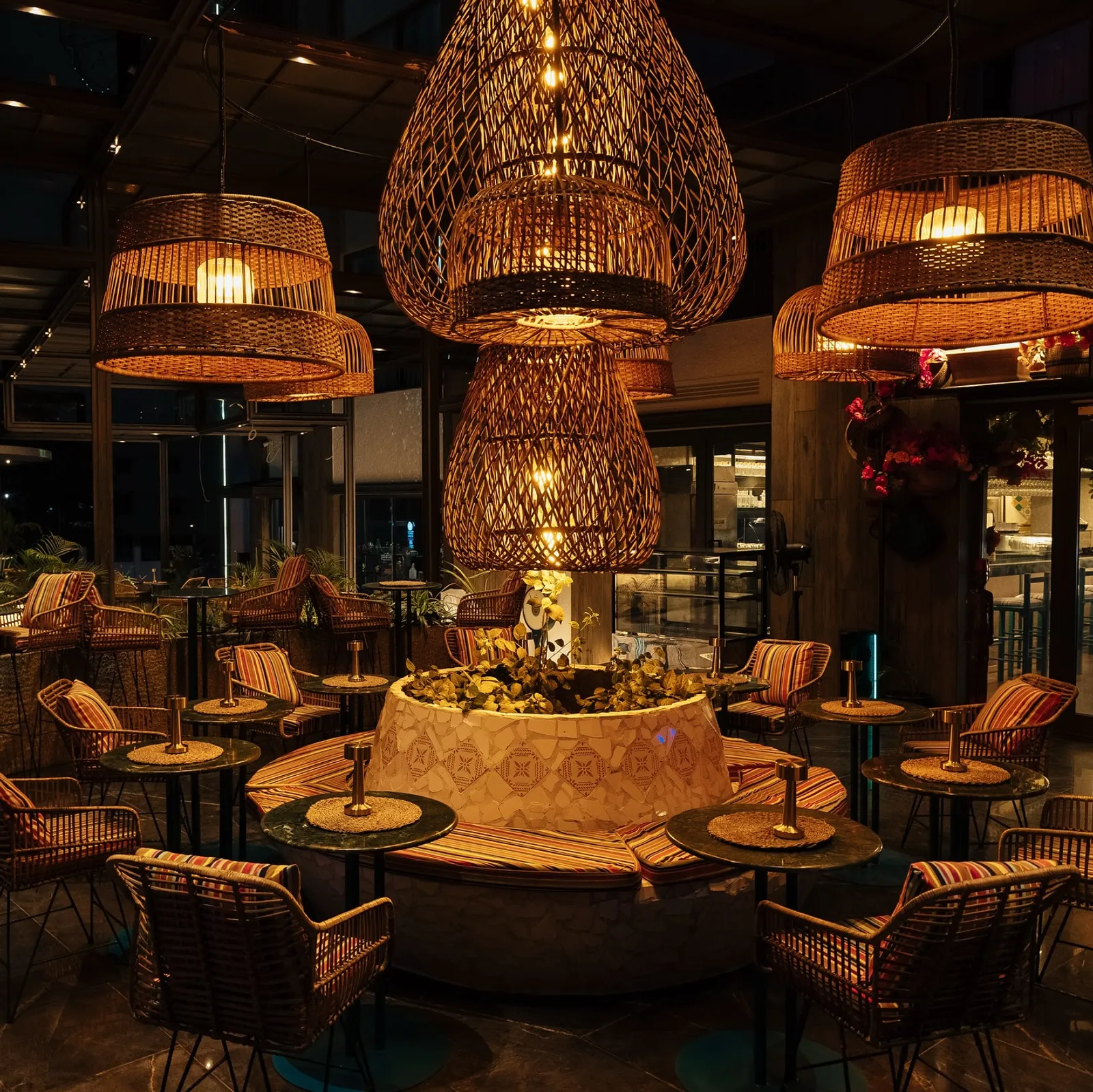 The courtyard at night — rattan lanterns glowing over the round mosaic table